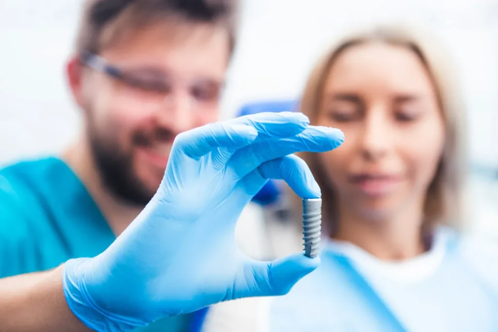 Implante dental de titanio sostenido por un odontólogo antes de colocarlo