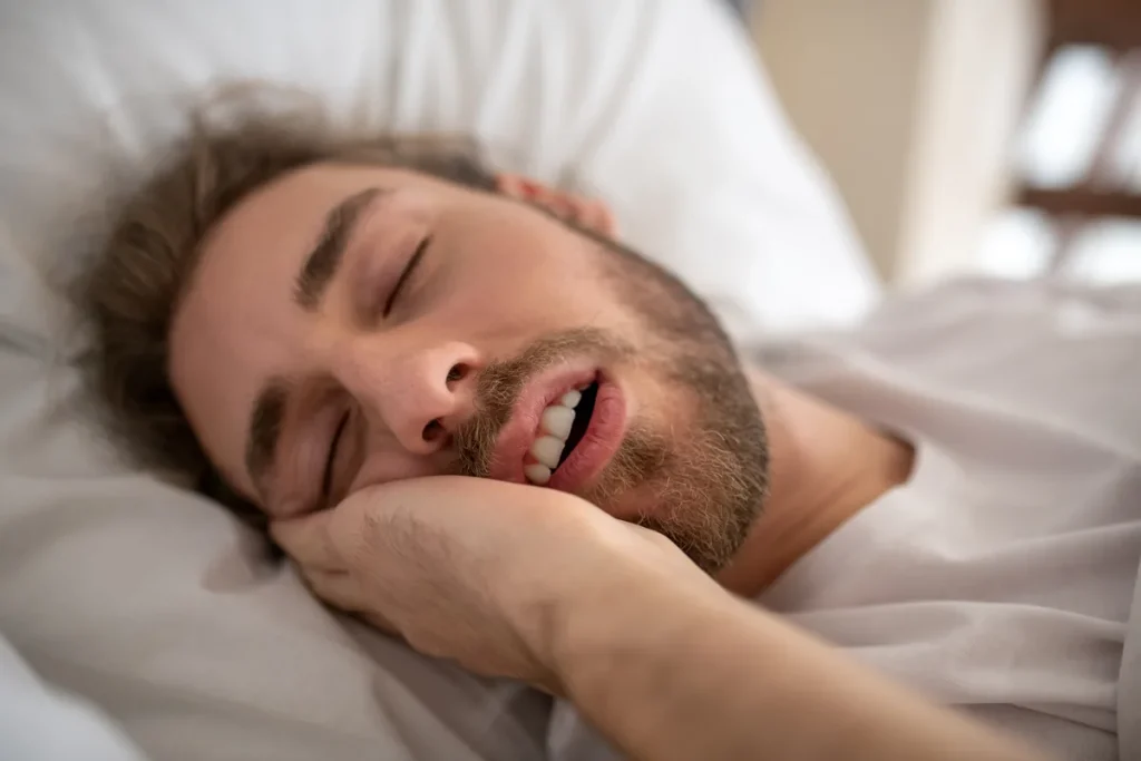Hombre dormido apretando los dientes: los ronquidos pueden ser señal de apnea del sueño